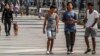 Jóvenes caminan por el Paseo del Prado mientras miembros de la policía patrullan en La Habana, el 11 de julio de 2022. (AP Foto/Ramon Espinosa)