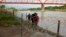Tres cubanos llegan a suelo estadounidense tras cruzar el Río bravo en Eagle Pass, Texas, el 22 de mayo de 2022. Al otro lado de la frontera muchos cubanos temen que un cambio migratorio les impida llegar a Estados Unidos. (AP Foto/Dario Lopez-Mills)