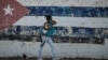 Una cubana camina ante un mural con la bandera cubana en La Habana. Foto Archivo (YAMIL LAGE / AFP)
