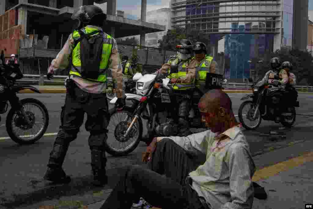 Vista de un hombre herido junto a miembros de la Guardia Nacional Bolivariana el jueves 20 de abril de 2017, en Caracas (Venezuela). La Guardia Nacional de Venezuela (GNB, policía militarizada) dispersó con gases lacrimógenos algunas concentraciones de opositores que se congregaban en diversos puntos de Caracas para marchar hacia la Defensoría del Pueblo, en el centro de la capital.