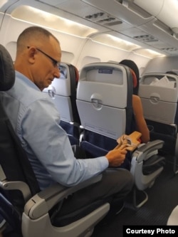 Ferrer sostiene un crucifijo de madera, en el avión en el que parte de Cuba al exilio.