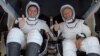 Los astronautas Robert Behnken (izq.) y Douglas Hurley saludan a su regreso a la Tierra dentro de la cápsula SpaceX Dragon.