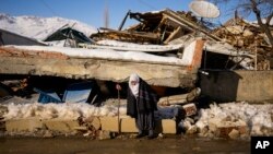 Zehra Kurukafa pasa junto a una casa destruida en la localidad de Polat, Turquía, el domingo 12 de febrero de 2023. (AP Foto/Francisco Seco)