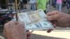 Un hombre muestra un peso convertible cubano y un dólar estadounidense. (Archivo)